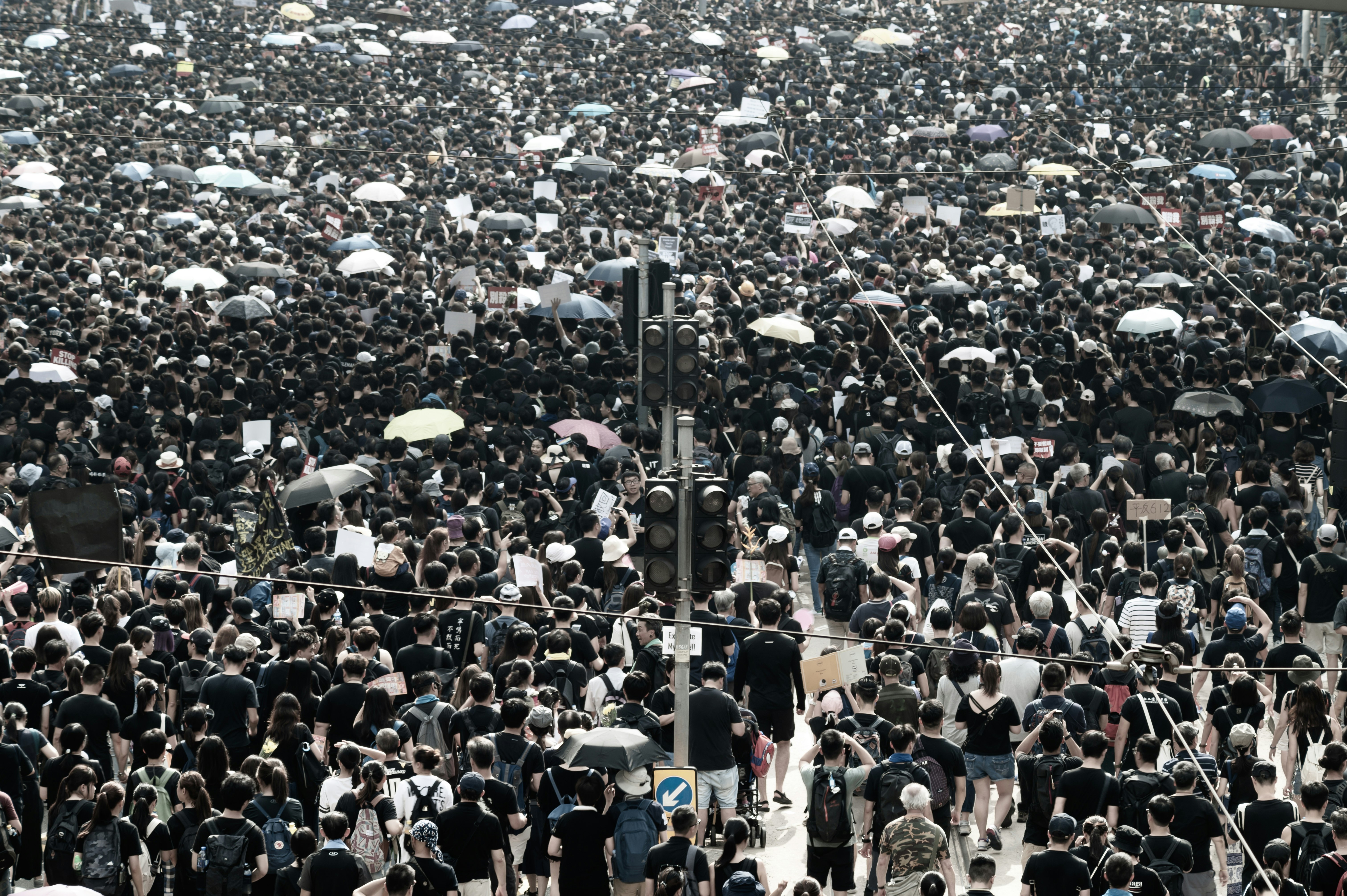 standing crowd, some using umbrellas